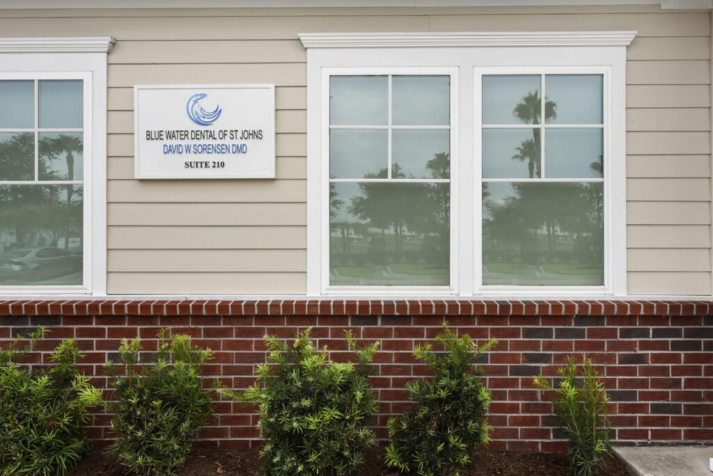 Outside wall with the Blue Water Dental of St. Johns sign between two windows