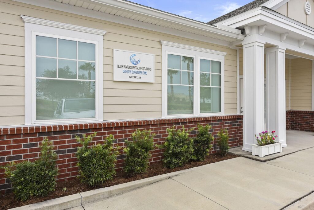 Building exterior with a brick base, shrubs and the practice sign