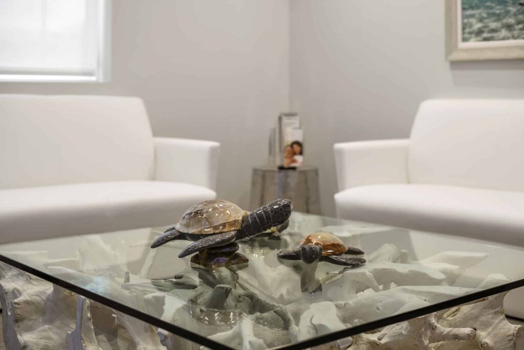 Lobby with white armchairs and a glass table holding sea turtle sculptures