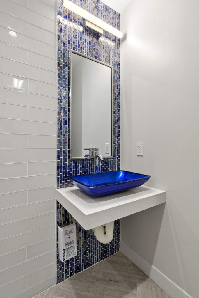 Patient restroom with a blue glass vessel sink and mosaic tile wall