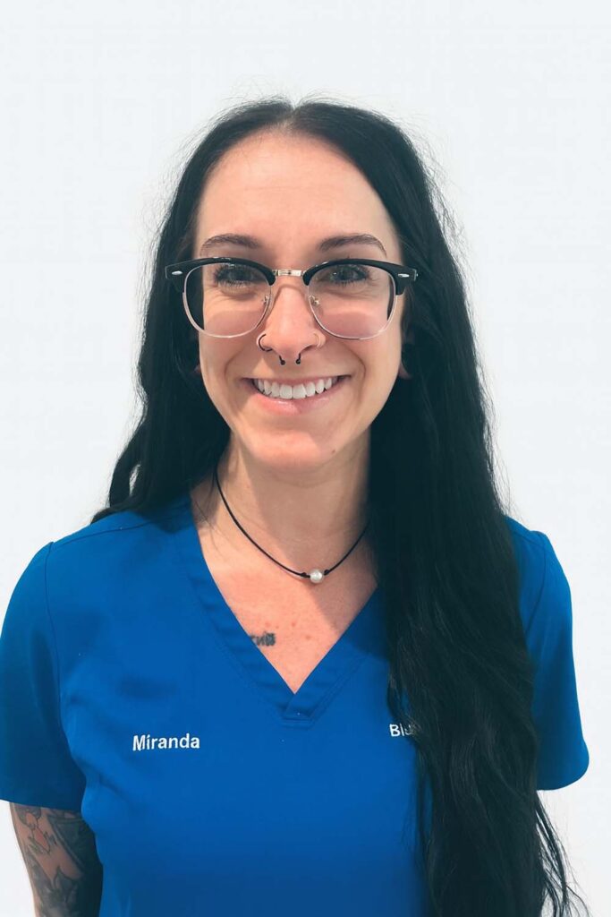 Miranda, dental assistant, in blue scrubs and glasses