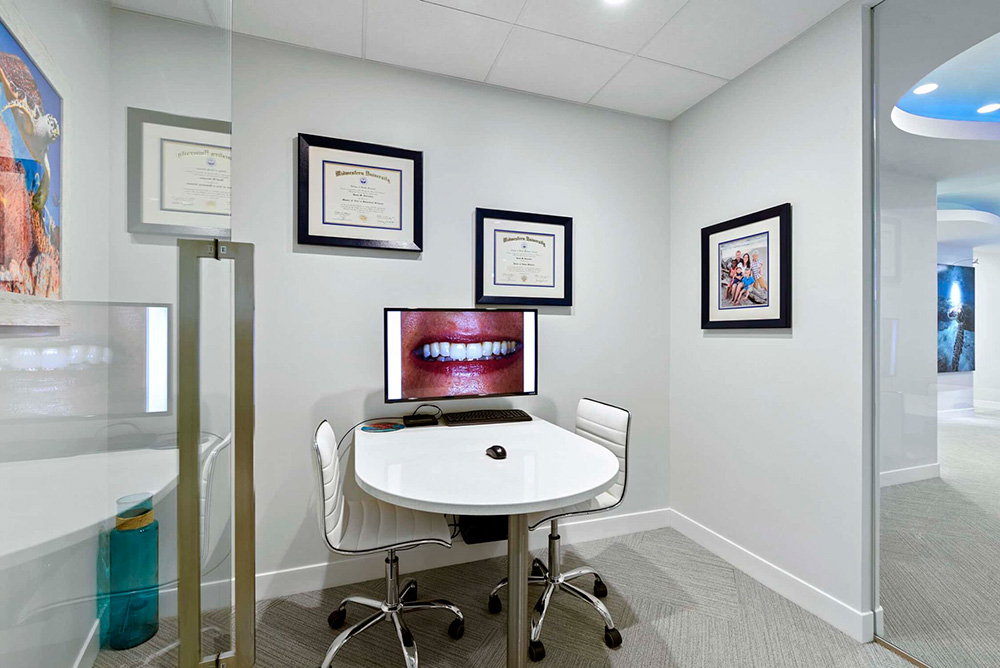 Consultation room with a round table, smile photo on screen and framed diplomas