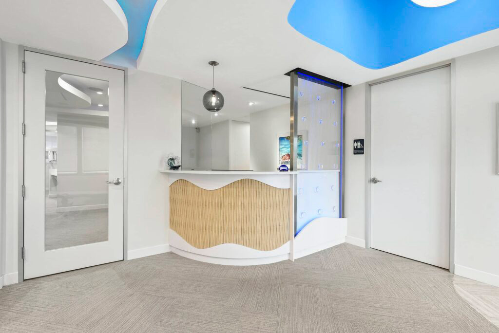 Bright reception area with a wave-shaped front desk and blue ceiling lighting
