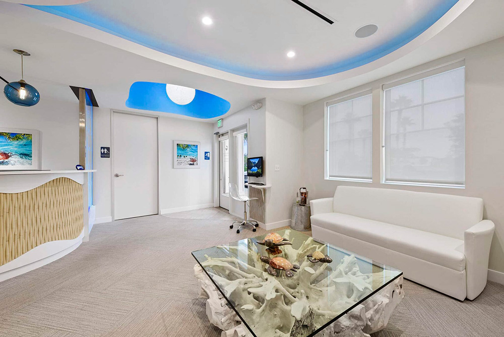 Waiting room with a white sofa, glass coffee table and the wave-shaped front desk