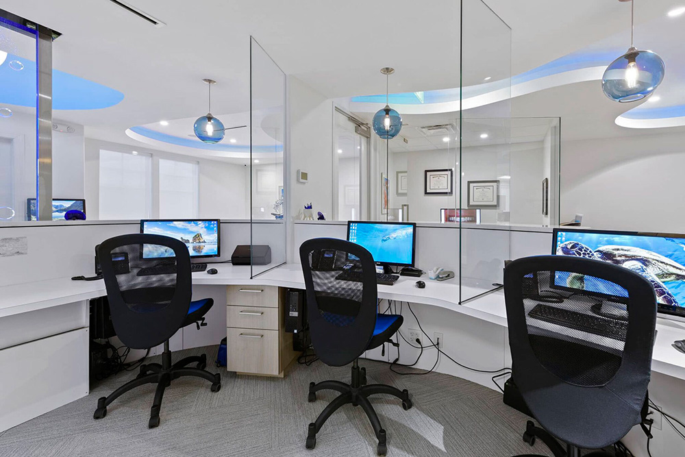 Front office workstations with three computers and blue pendant lights